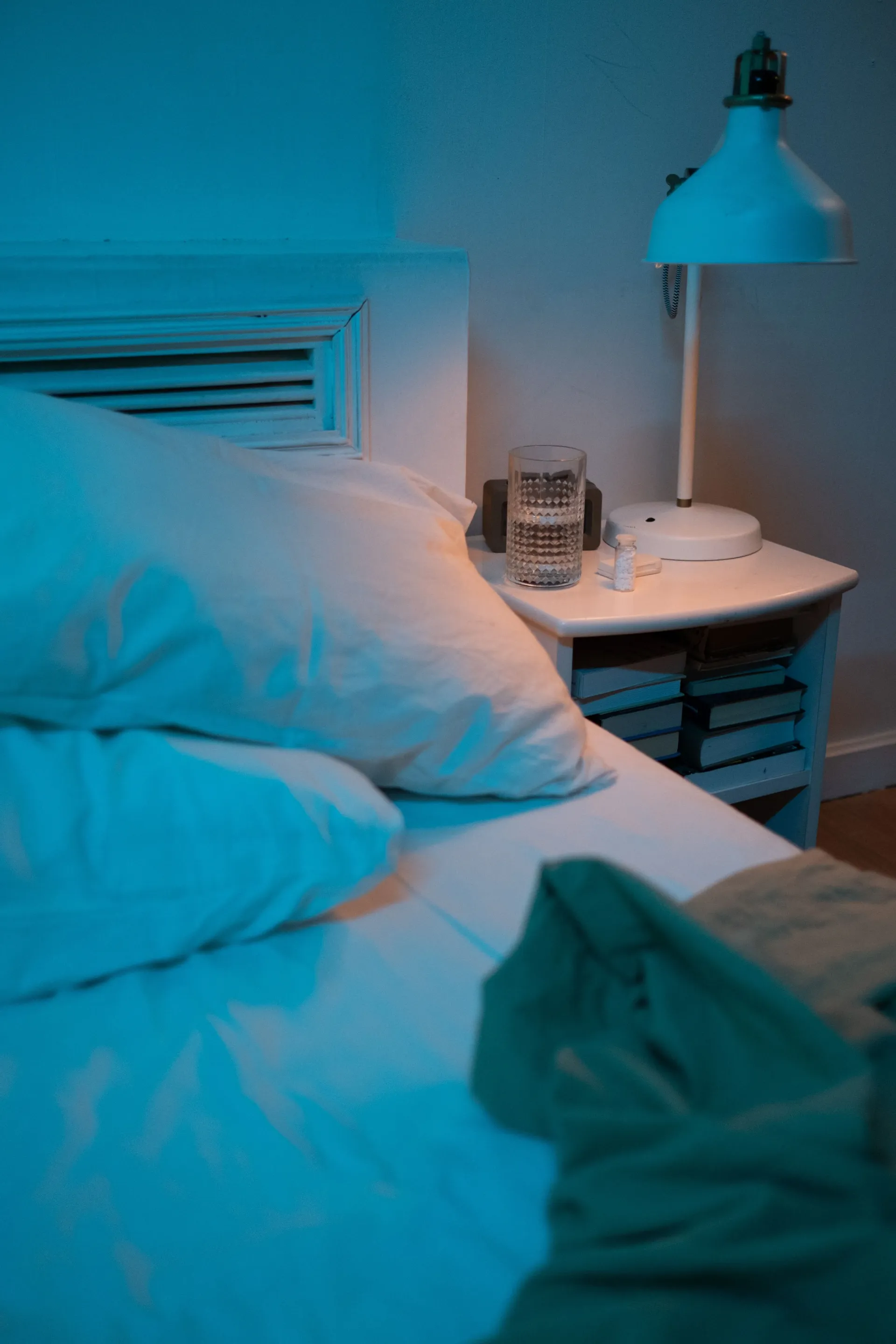 Verre d’eau posé sur une table de chevet pour illustrer le repos après un lendemain de veille