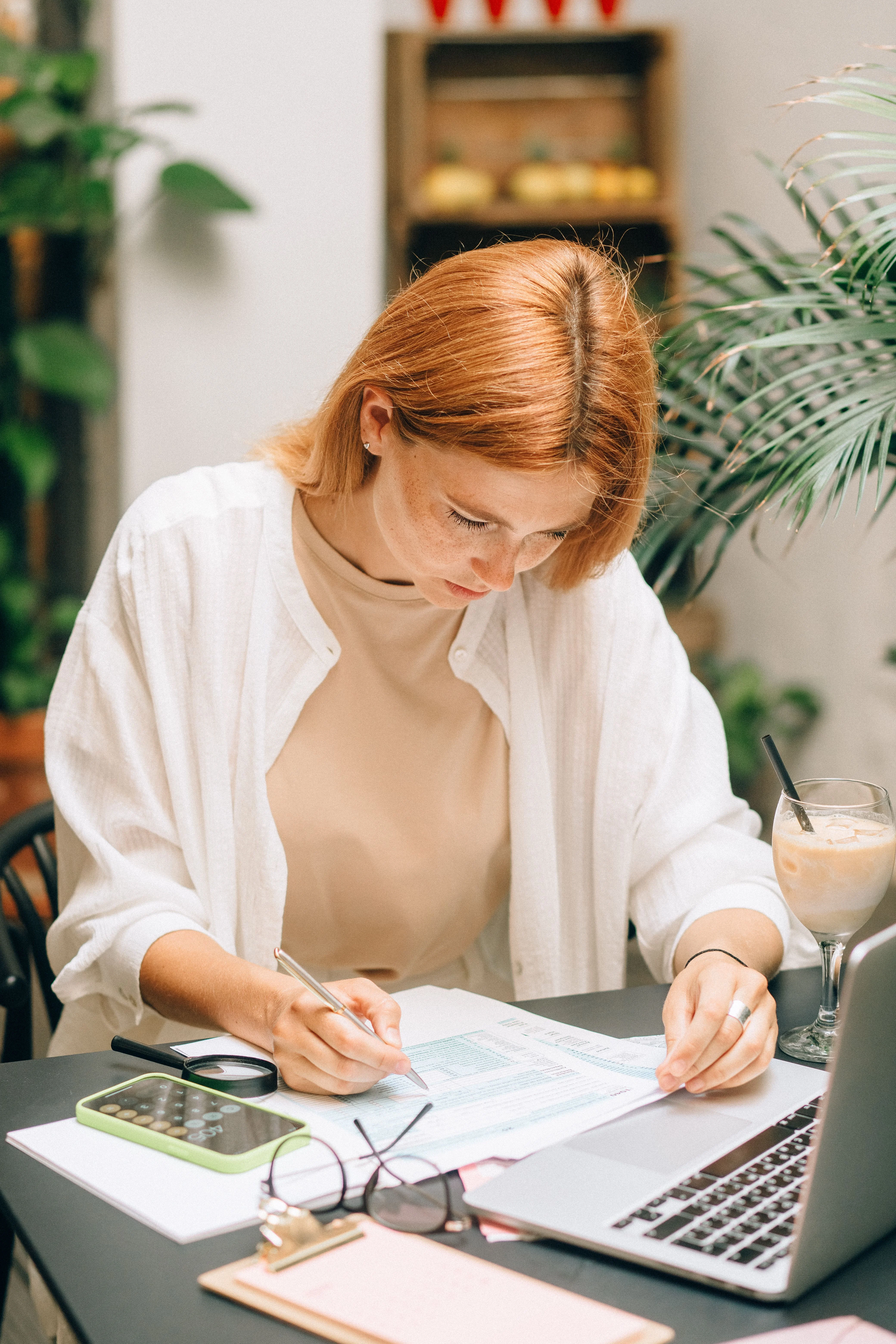 Personne consultant des documents avec un ordinateur et une calculatrice pour pr&eacute;parer ses d&eacute;marches de prime d&rsquo;activit&eacute;
